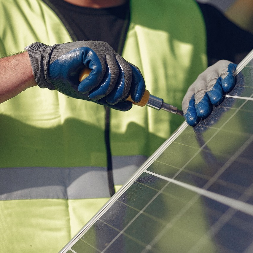 Dachdecker montiert ein Solarmodul auf einem Flachdach – Photovoltaik-Installation FuB Wiesbaden