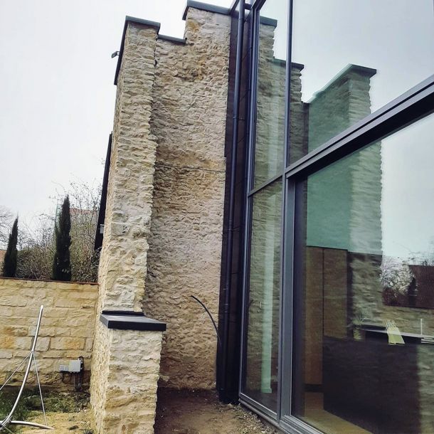 Modernisierte Natursteinarchitektur mit großzügiger Glasfassade und fachgerecht ausgeführtem Flachdach